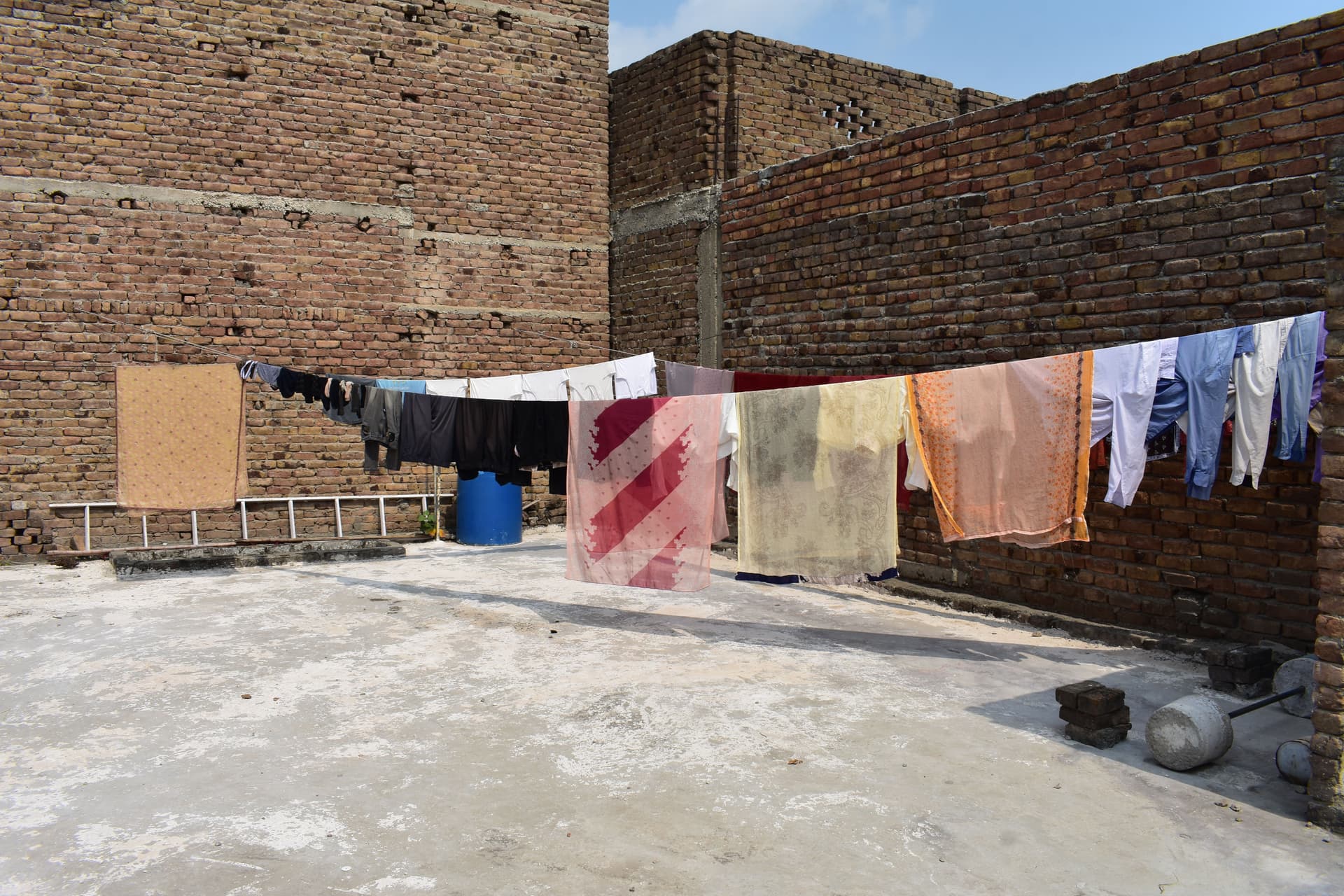 Laundry hanging out to dry on a line beside a brick wall under a bright sky.